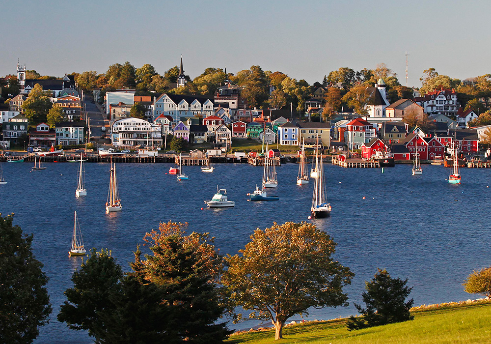 An image rendering of sail boats and colourful houses in Lunenburg, on a sunny day.