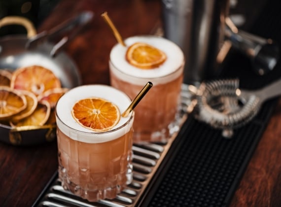 Two mixed drinks on a bar rail