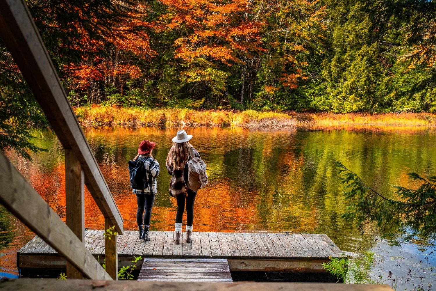 Two people experiencing fall colours at a lake
